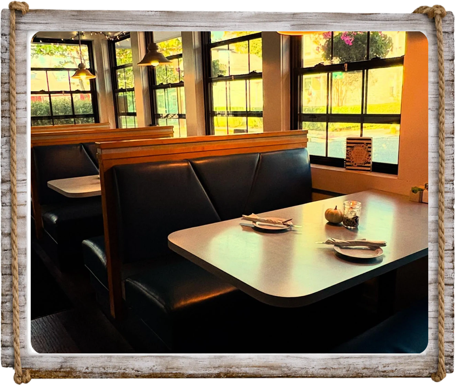 Cozy restaurant booth with black leather seats and a white table set for four.