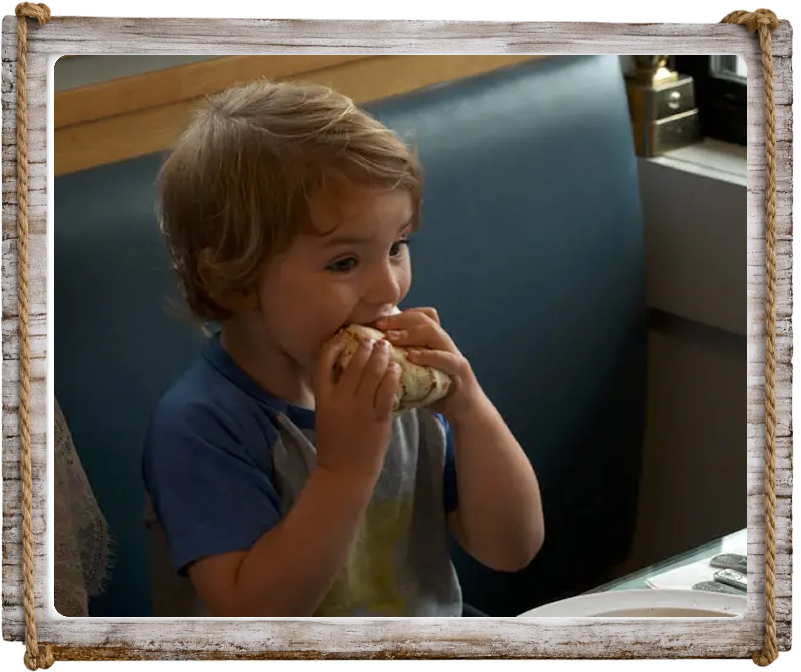 A young child eating a sandwich with focus.