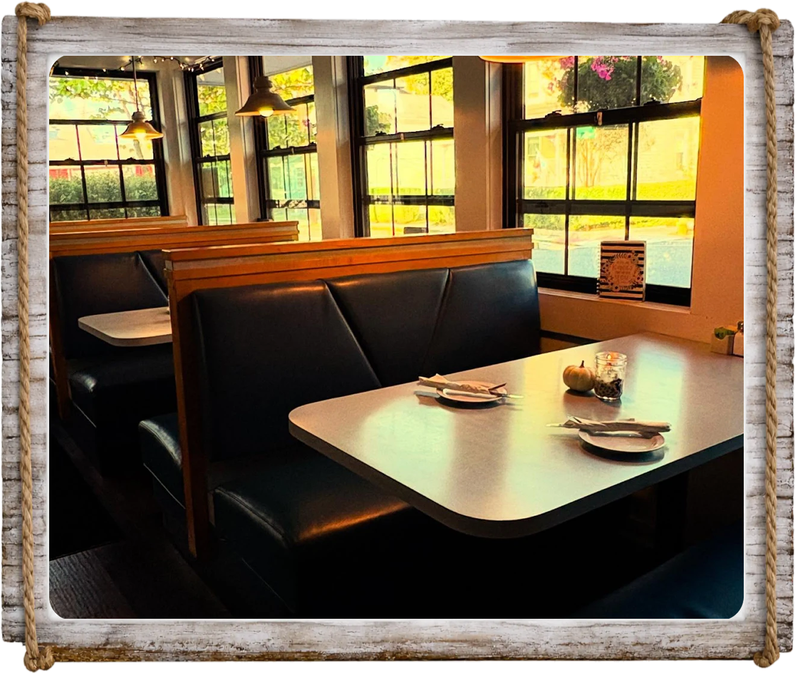 Cozy restaurant booth with warm sunlight through large windows.