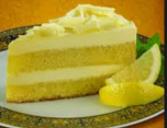 A slice of creamy lemon cake with frosting and lemon wedges.