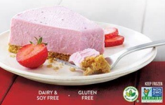 Slice of pink strawberry cheesecake on a white plate with fresh strawberries.