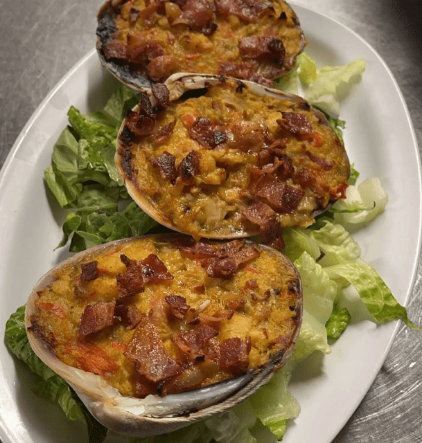 Three stuffed baked potatoes with cheese and bacon on lettuce.