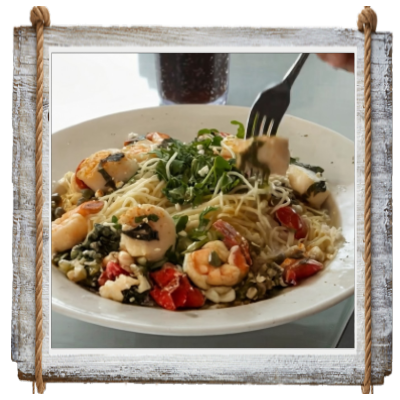 A bowl of shrimp pasta garnished with herbs and sun-dried tomatoes.