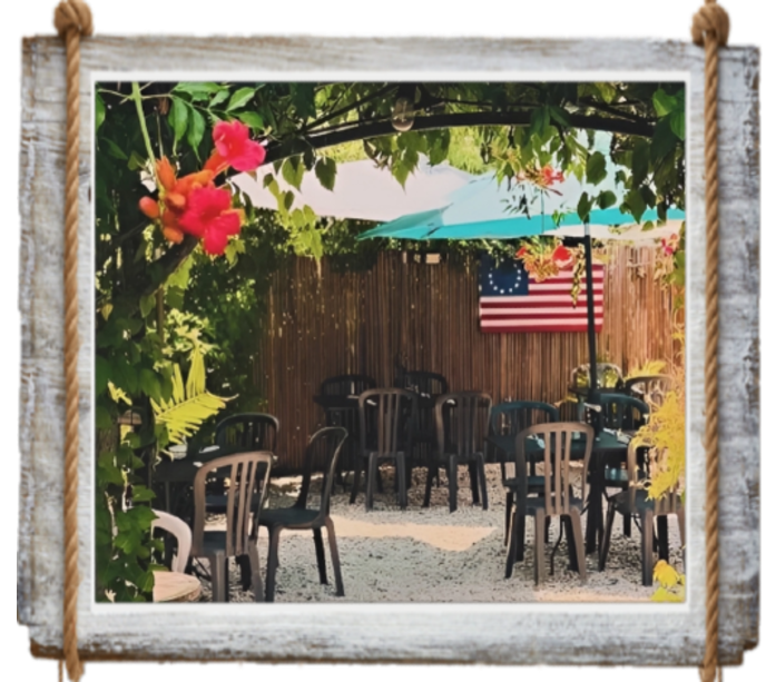 Outdoor seating area with black chairs, flowers, and an American flag.