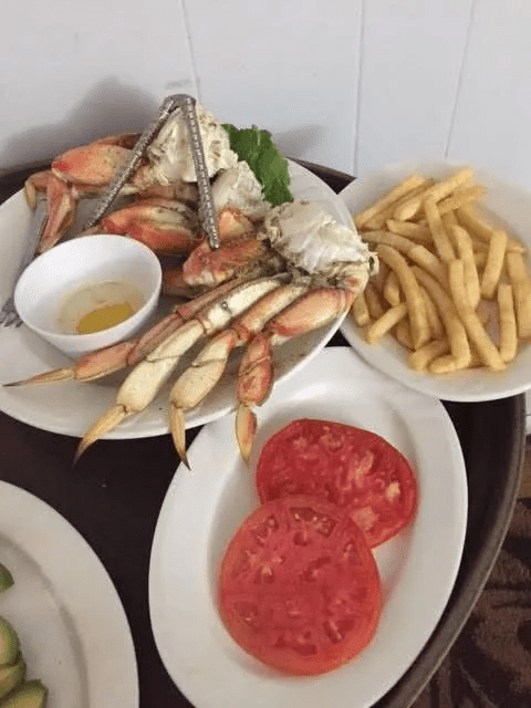 A seafood meal with crab legs, fries, and sliced tomatoes.