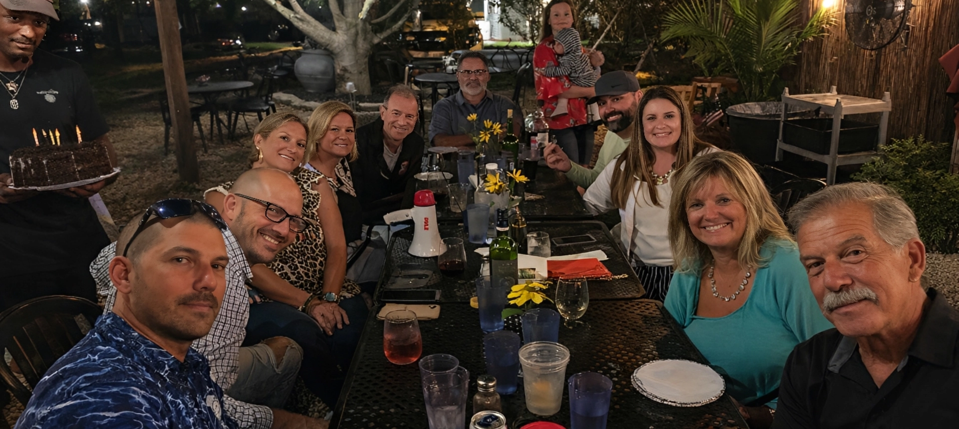 Group of friends enjoying a lively outdoor dinner at night.