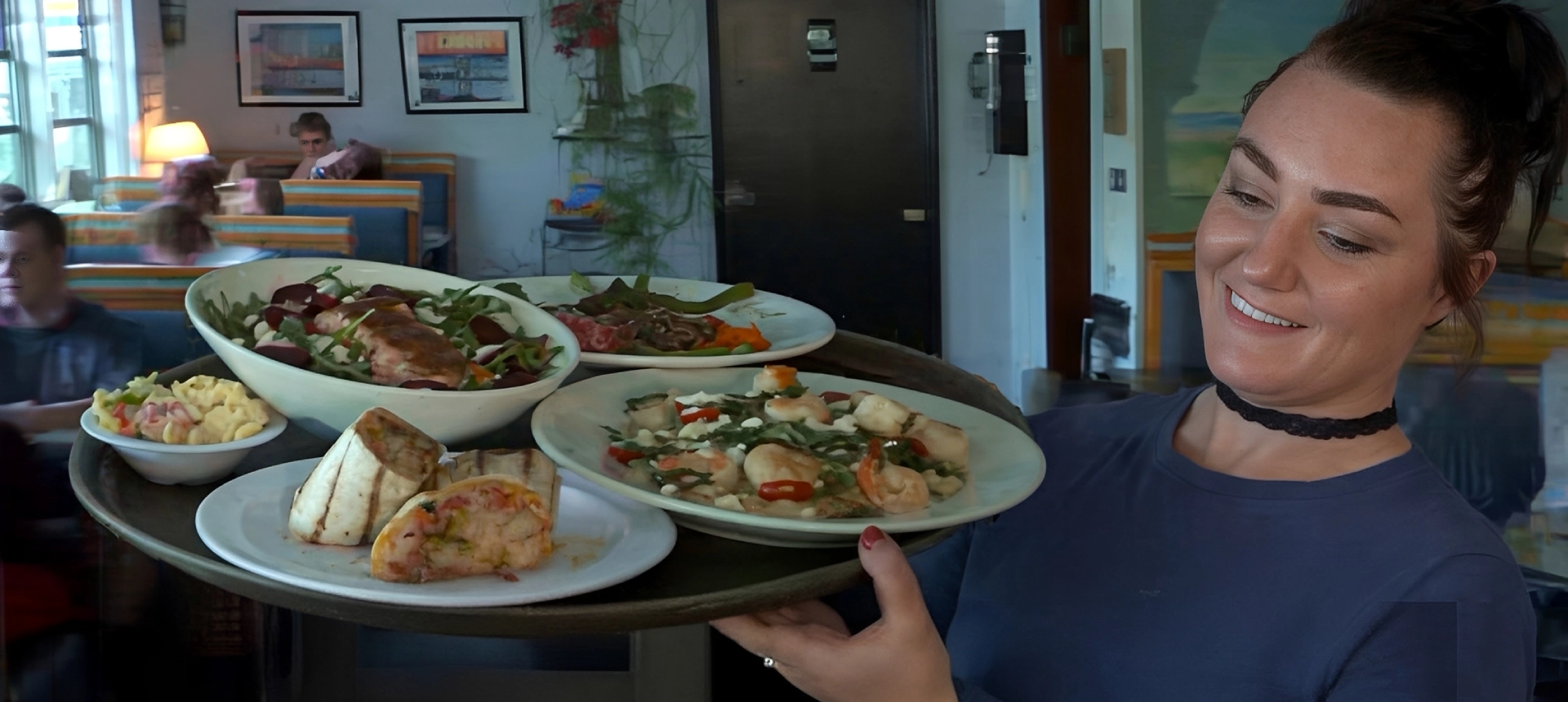 A waiter carrying a tray with various dishes in a restaurant.