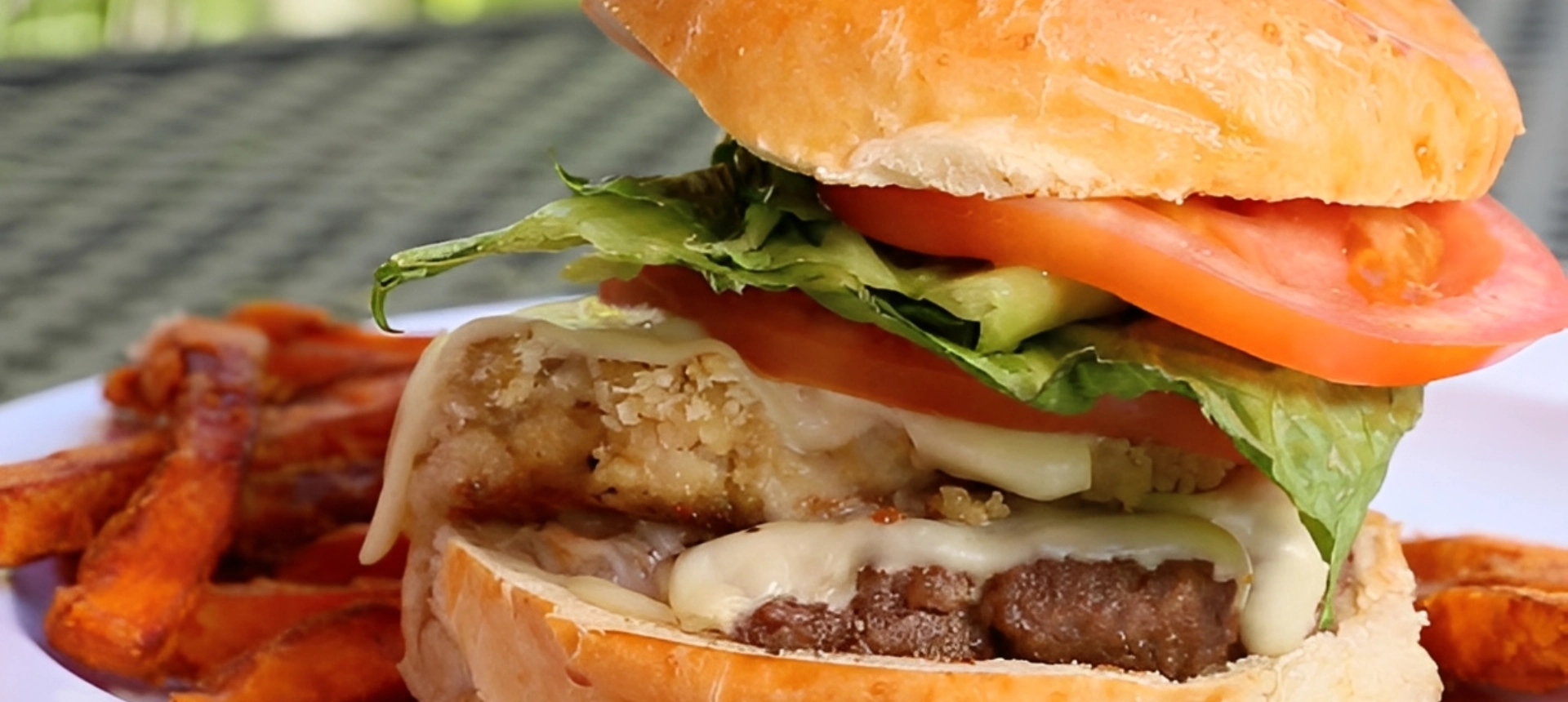 Close-up of a juicy cheeseburger with lettuce and tomato.